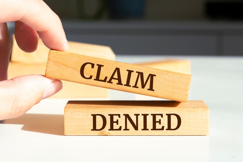 Wooden blocks with words 'CLAIM DENIED'