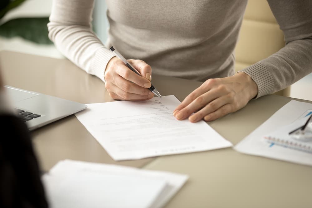 Woman signing documents after successful negotiations with the insurance company