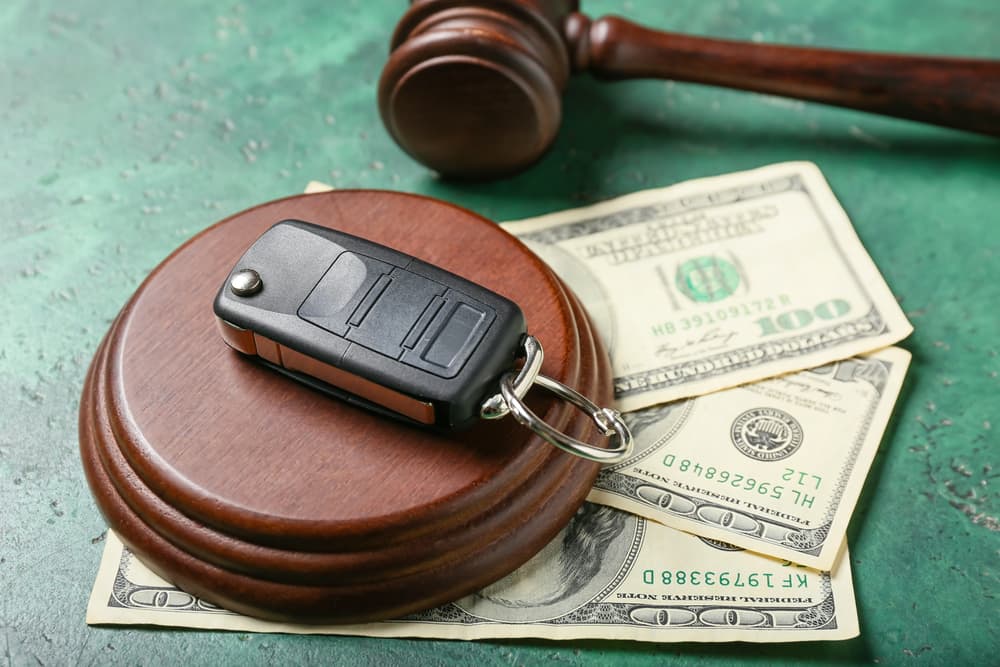 Wooden gavel along with car key and dollar amount 